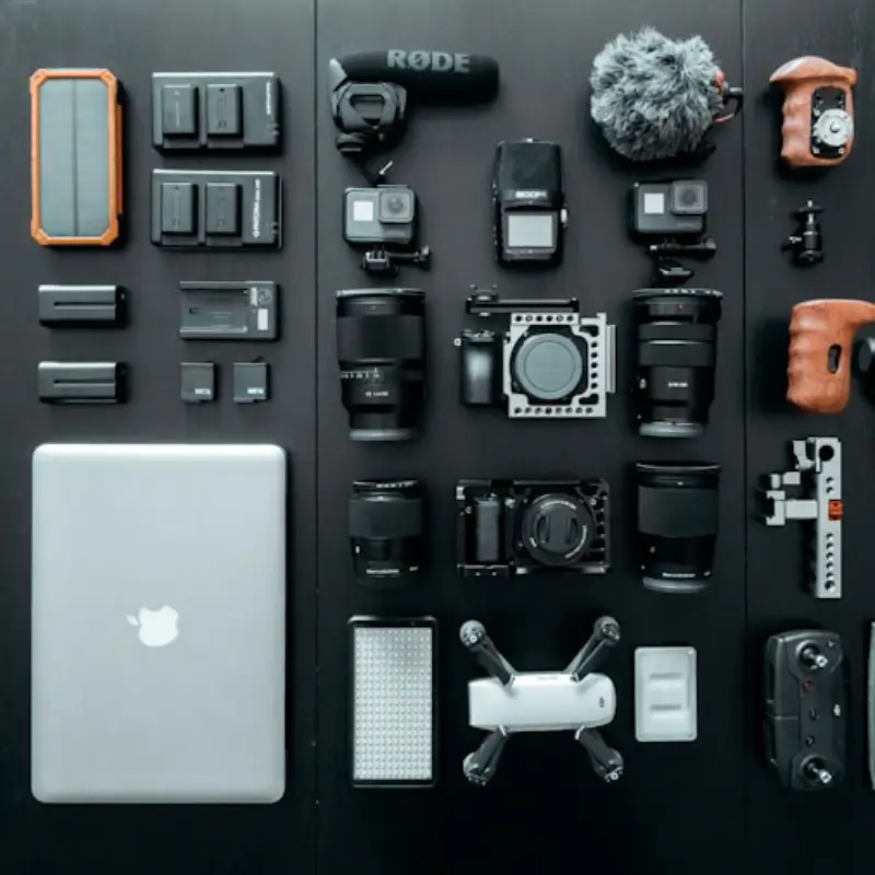 Silver MacBook beside battery charger, cameras, microphone and other accessories